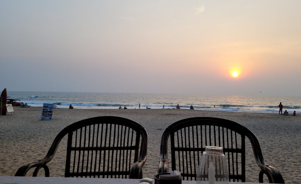 Bild zeigt zwei Stühle am Strand in Goa mit einem Sonnenuntergang